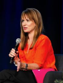 Image of Lynn Meskell, seated, holding microphone